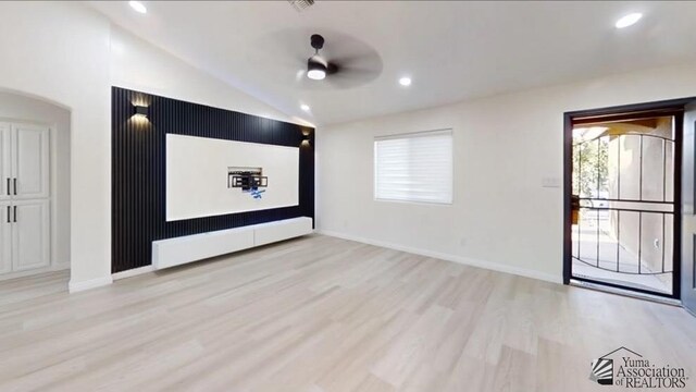 home theater featuring light wood-type flooring, ceiling fan, and lofted ceiling