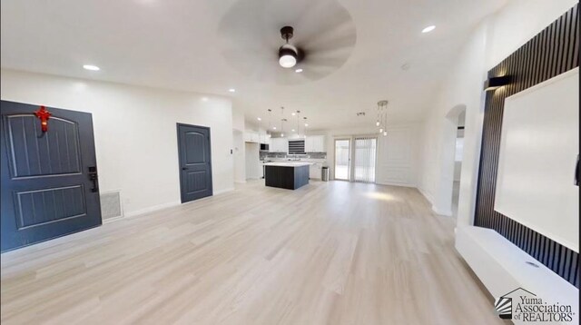 unfurnished living room featuring ceiling fan and light wood-type flooring