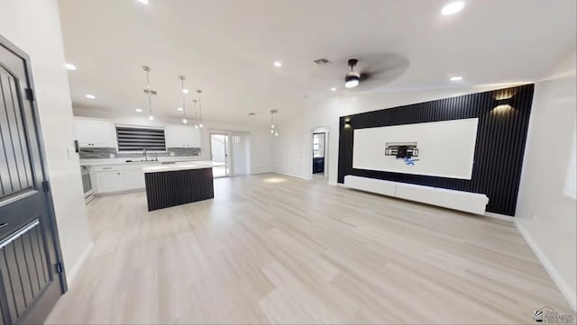 kitchen with vaulted ceiling, ceiling fan, decorative light fixtures, a center island, and white cabinetry