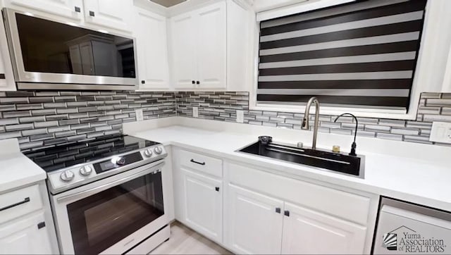 kitchen with white cabinets, appliances with stainless steel finishes, backsplash, and sink