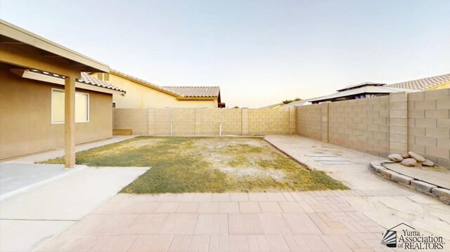 yard at dusk featuring a patio area