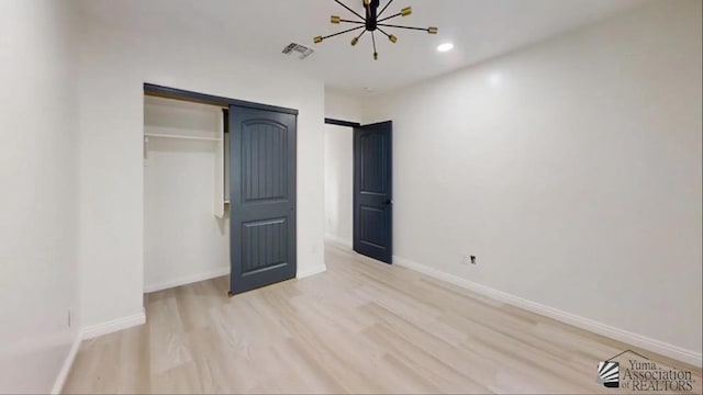 unfurnished bedroom featuring a closet, a chandelier, and light hardwood / wood-style flooring