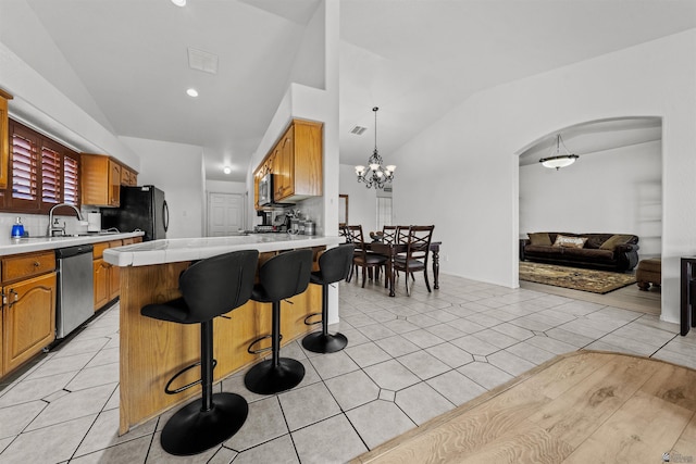 3875 W 26th St, Yuma, AZ 85364 - kitchen with stainless steel appliances, vaulted ceiling, light countertops, a breakfast bar area, and arched walkways