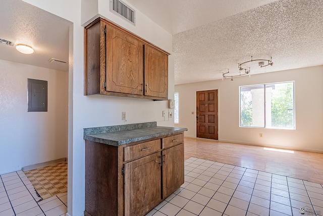2231 S Elks Ln # 77, Yuma, AZ 85364 - kitchen featuring electric panel, light tile patterned flooring, a textured ceiling, dark countertops, and brown cabinetry
