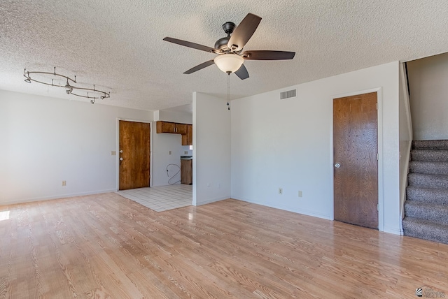 2231 S Elks Ln # 77, Yuma, AZ 85364 - unfurnished living room featuring ceiling fan, light wood-style flooring, stairway, and a textured ceiling