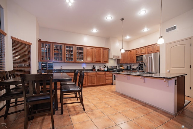 kitchen with visible vents, appliances with stainless steel finishes, brown cabinets, custom exhaust hood, and a breakfast bar