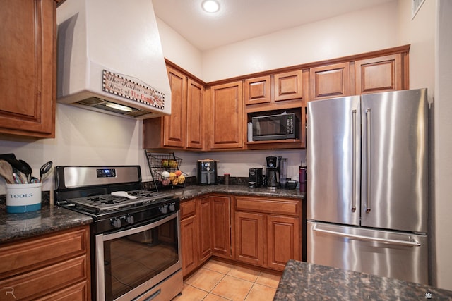 kitchen featuring brown cabinetry, appliances with stainless steel finishes, light tile patterned floors, and exhaust hood
