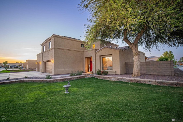 view of front of home featuring fence, a garage, stucco siding, a yard, and driveway