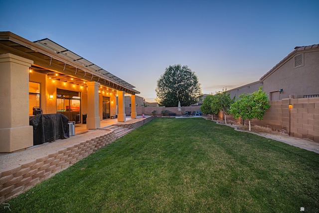 yard at dusk with a fenced backyard and a patio