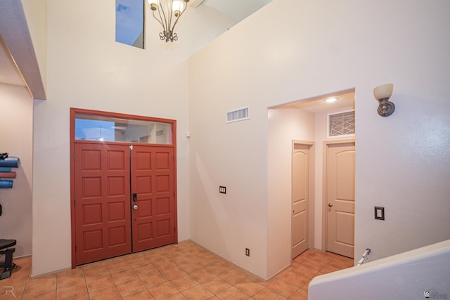 foyer with visible vents, a high ceiling, and light tile patterned flooring
