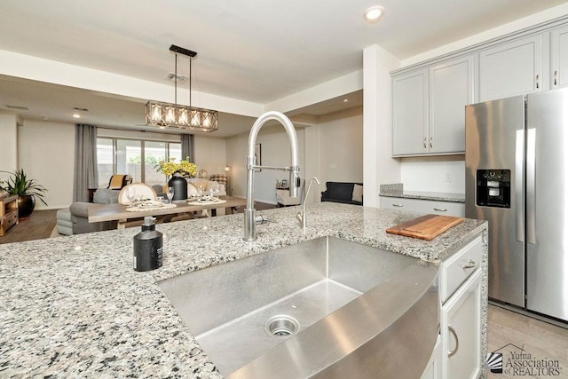 12160 S Drucilla Ln, Yuma, AZ 85367 - kitchen with stainless steel fridge with ice dispenser, open floor plan, hanging light fixtures, light stone countertops, and recessed lighting