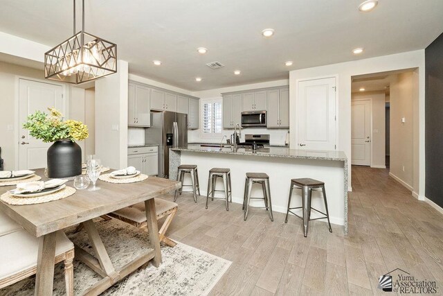 12160 S Drucilla Ln, Yuma, AZ 85367 - kitchen featuring appliances with stainless steel finishes, gray cabinetry, a breakfast bar, light wood-style flooring, and recessed lighting