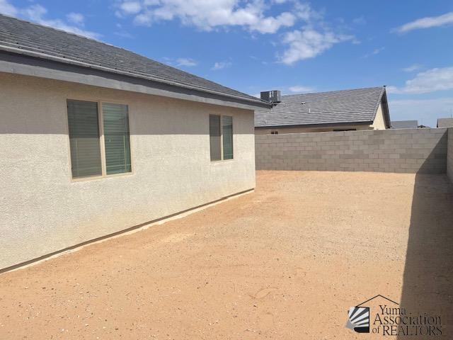 4680 E San Pedro St, San Luis, AZ 85336 - view of property exterior with stucco siding, roof with shingles, and a fenced backyard