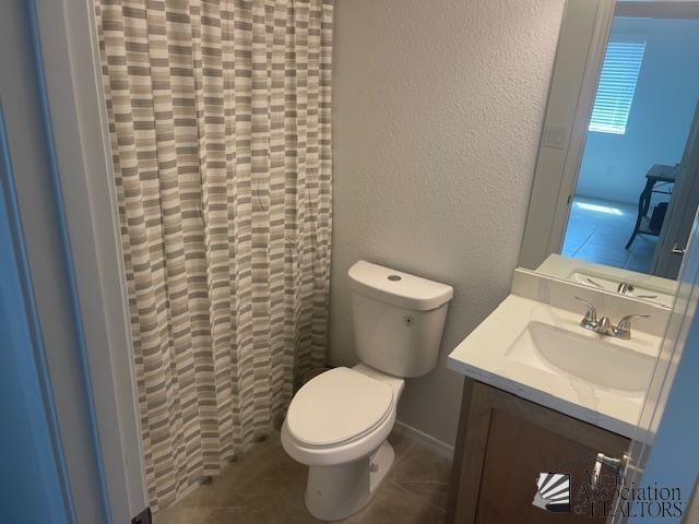 4680 E San Pedro St, San Luis, AZ 85336 - bathroom with toilet, baseboards, curtained shower, vanity, and a textured wall