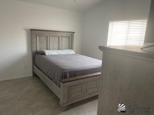 4680 E San Pedro St, San Luis, AZ 85336 - bedroom featuring light tile patterned floors, baseboards, and lofted ceiling
