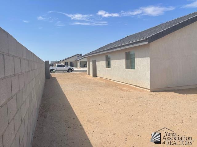 4680 E San Pedro St, San Luis, AZ 85336 - view of side of home with stucco siding, roof with shingles, and fence