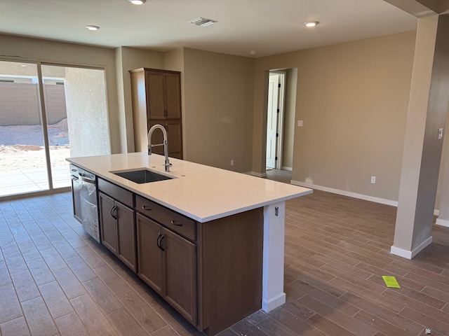 kitchen with visible vents, stainless steel dishwasher, a sink, baseboards, and dark wood-type flooring