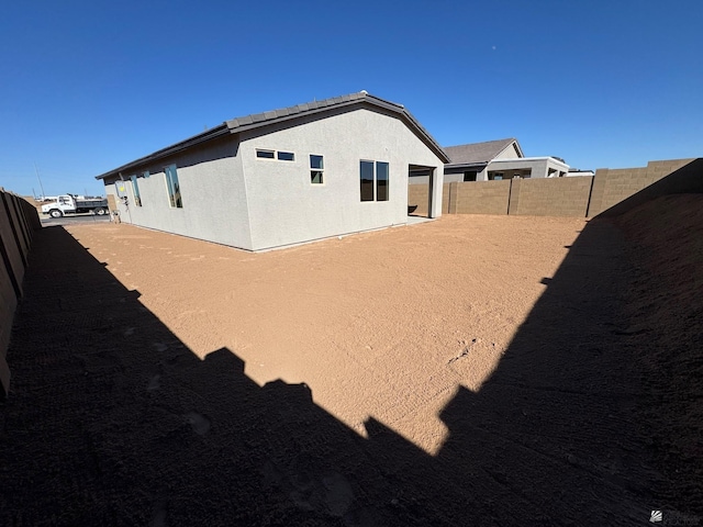 back of property featuring fence and stucco siding