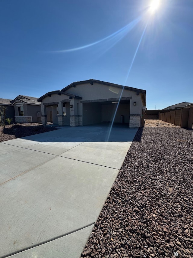view of front facade featuring a garage, fence, concrete driveway, and stone siding