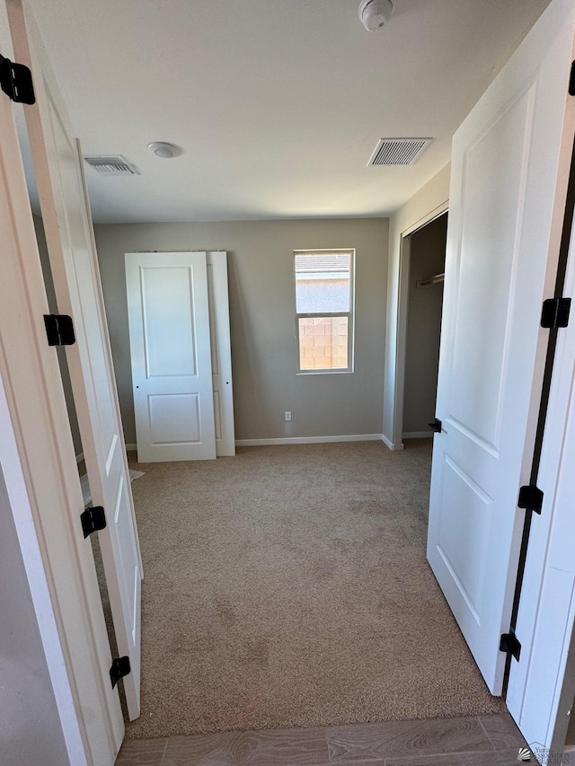 unfurnished bedroom with carpet flooring, baseboards, and visible vents
