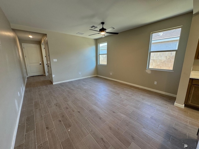 interior space featuring a ceiling fan, baseboards, visible vents, and wood finished floors