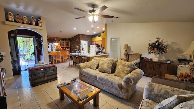living room with ceiling fan, visible vents, light tile patterned floors, and lofted ceiling
