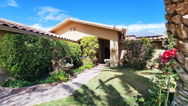 exterior space with roof mounted solar panels, stucco siding, and a tiled roof