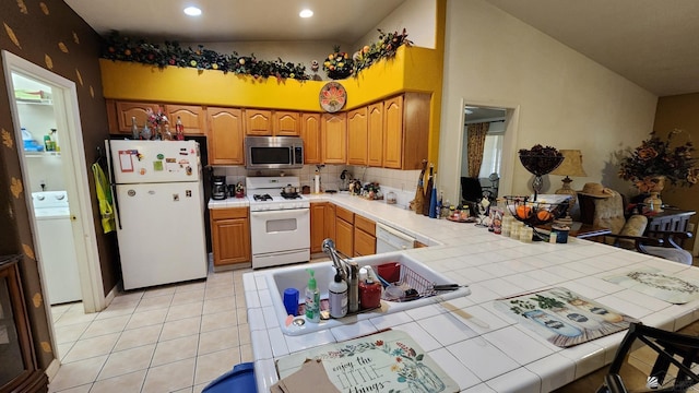 kitchen featuring white appliances, tile counters, decorative backsplash, and a peninsula