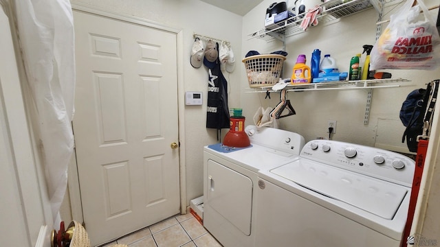 clothes washing area featuring laundry area, light tile patterned flooring, and washing machine and clothes dryer