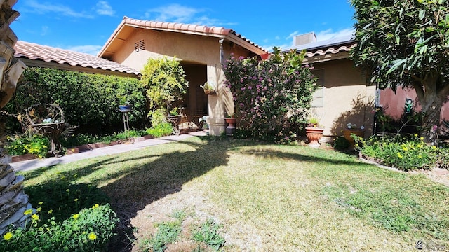 exterior space with roof mounted solar panels, stucco siding, a tiled roof, and a front yard