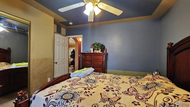 bedroom featuring a closet, arched walkways, and ceiling fan