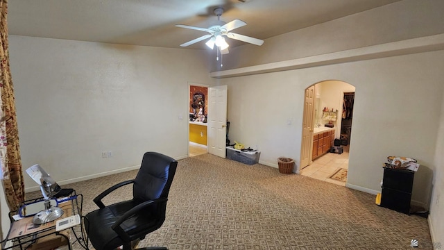 office area with arched walkways, a ceiling fan, light colored carpet, and baseboards