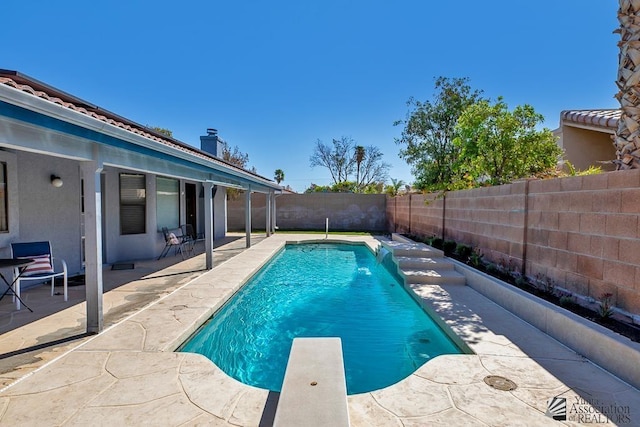 view of pool featuring a patio, a fenced backyard, a diving board, and a fenced in pool
