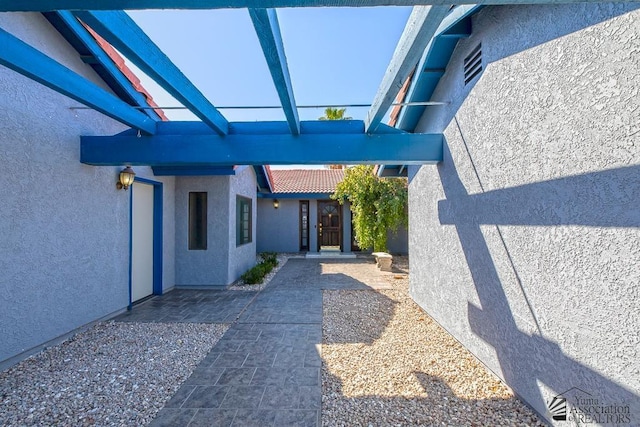 view of exterior entry with a patio area and stucco siding