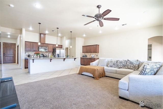 living room featuring light tile patterned flooring, arched walkways, a ceiling fan, recessed lighting, and visible vents