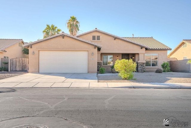 ranch-style home with a tiled roof, fence, concrete driveway, an attached garage, and stucco siding