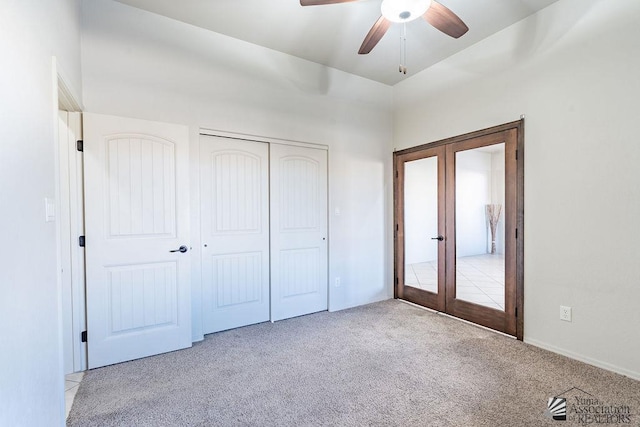 unfurnished bedroom with a closet, a ceiling fan, french doors, and carpet flooring