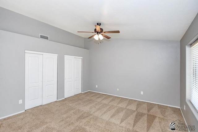 6257 E 47th St, Yuma, AZ 85365 - unfurnished bedroom with two closets, lofted ceiling, carpet, multiple windows, and ceiling fan