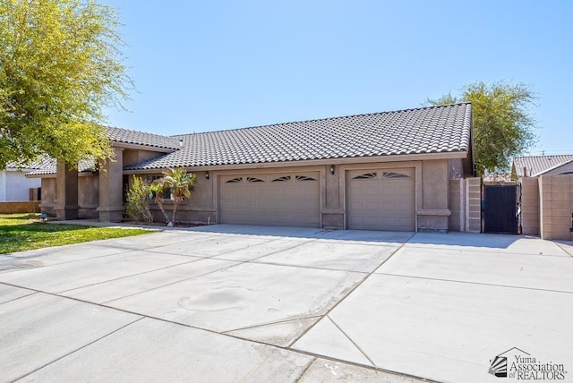 6257 E 47th St, Yuma, AZ 85365 - view of front facade with concrete driveway, a tile roof, a gate, an attached garage, and stucco siding