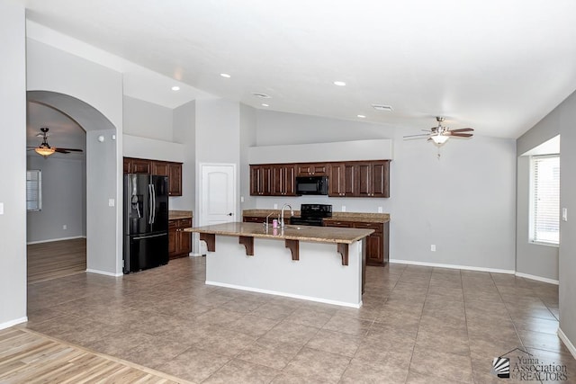 6257 E 47th St, Yuma, AZ 85365 - kitchen with black appliances, ceiling fan, vaulted ceiling, a center island with sink, and a kitchen bar