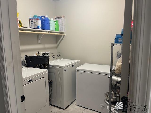 clothes washing area with light tile patterned floors, laundry area, and washer and clothes dryer