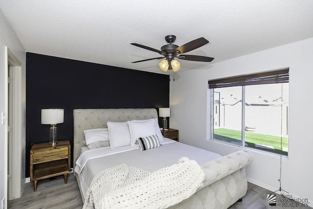 bedroom with a textured ceiling, baseboards, a ceiling fan, and wood finished floors