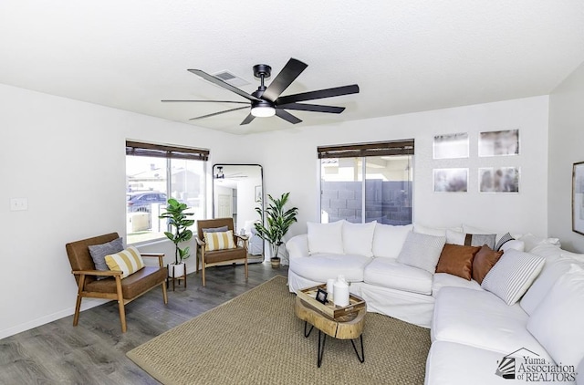 living room with baseboards, a ceiling fan, wood finished floors, and a wealth of natural light
