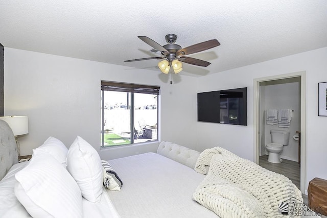 bedroom featuring a textured ceiling, ensuite bathroom, a ceiling fan, and wood finished floors