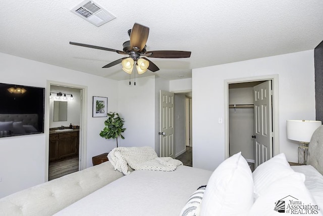 bedroom featuring a sink, a ceiling fan, ensuite bathroom, visible vents, and a closet