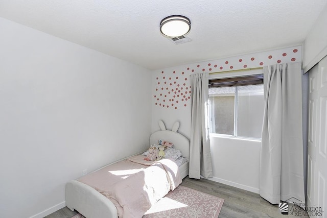 bedroom featuring baseboards, wood finished floors, and visible vents