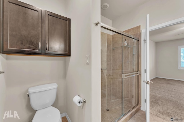 full bath featuring toilet, baseboards, and a shower stall