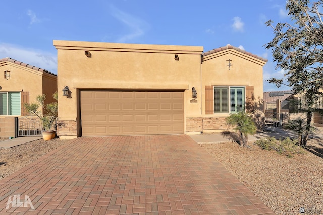 view of front of home featuring stucco siding, an attached garage, decorative driveway, and stone siding