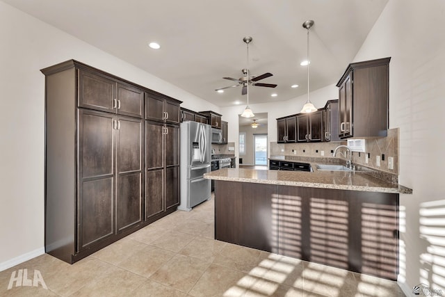 kitchen with dark brown cabinetry, light stone counters, a sink, stainless steel appliances, and a ceiling fan