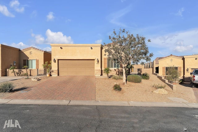 pueblo revival-style home featuring an attached garage, decorative driveway, and stucco siding
